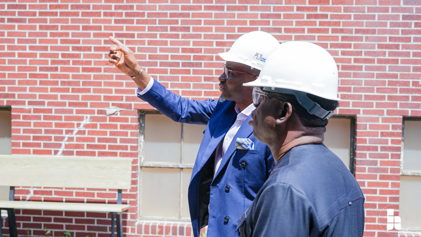 Jubilee Place leaders in hard hats surveying the church building against bare brick