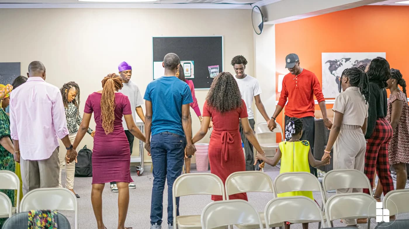 Members standing in a circle holding hands before a service