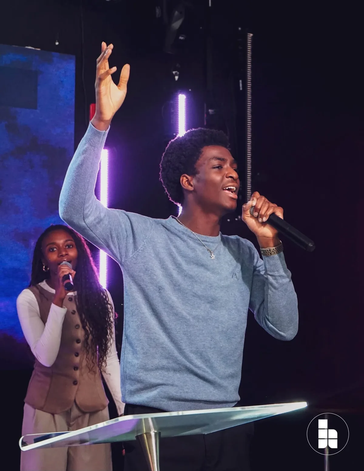 A young worship leader singing with a hand raised
